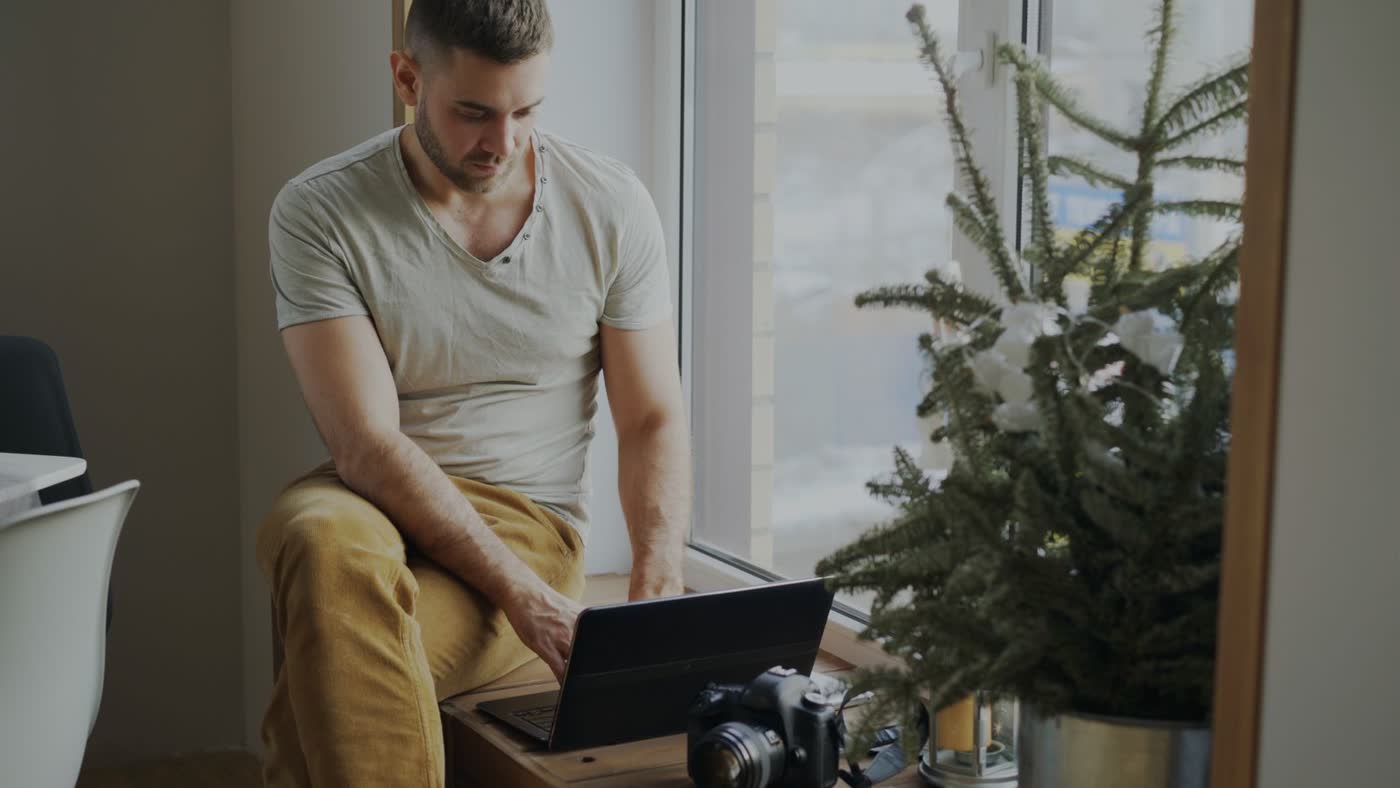 Een zelfstandige werkt op zijn laptop aan een zonnig raam